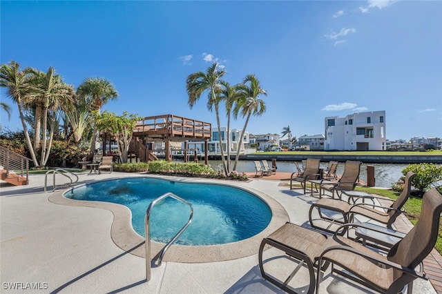 view of pool featuring a water view and a patio