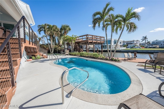 view of pool featuring a water view and a patio