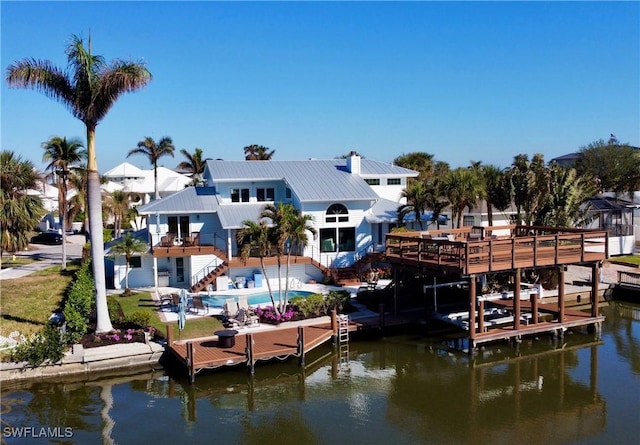 view of dock featuring an outdoor pool, a balcony, boat lift, stairway, and a water view