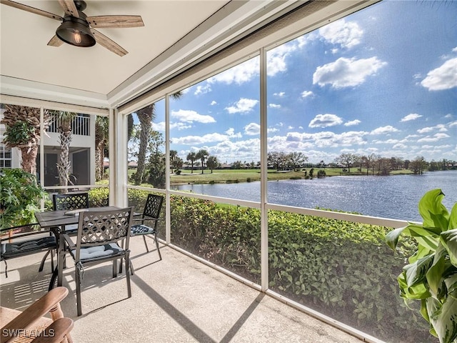 sunroom / solarium with ceiling fan and a water view