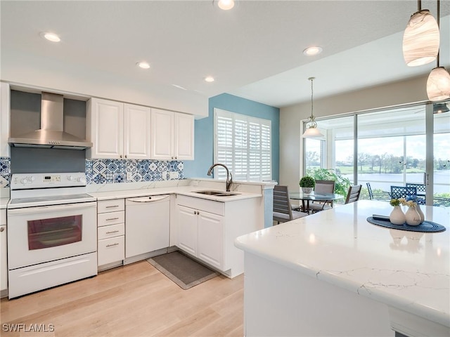 kitchen with white cabinets, wall chimney exhaust hood, white appliances, and sink