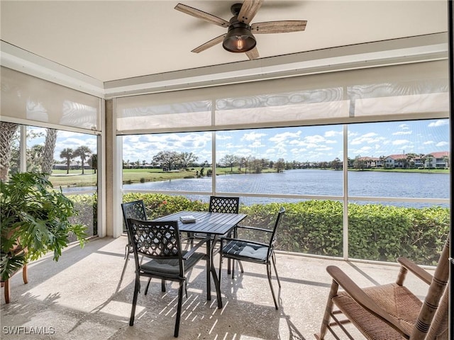 sunroom with ceiling fan and a water view