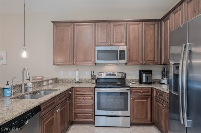 kitchen featuring stainless steel appliances, hanging light fixtures, sink, light tile patterned flooring, and light stone countertops