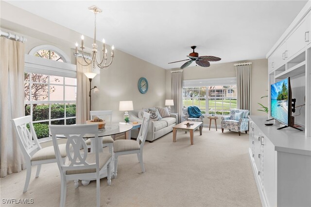 carpeted dining space with ceiling fan with notable chandelier