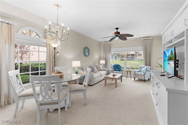 dining area featuring ceiling fan with notable chandelier and light carpet