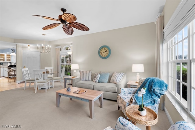 living room with light carpet and ceiling fan with notable chandelier