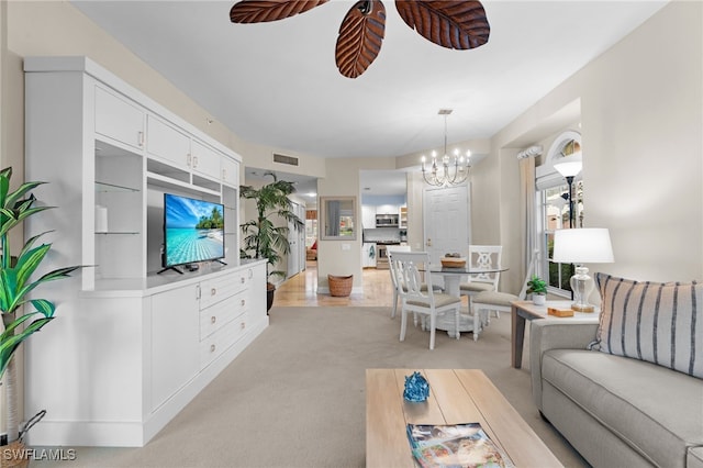 carpeted living room featuring ceiling fan with notable chandelier