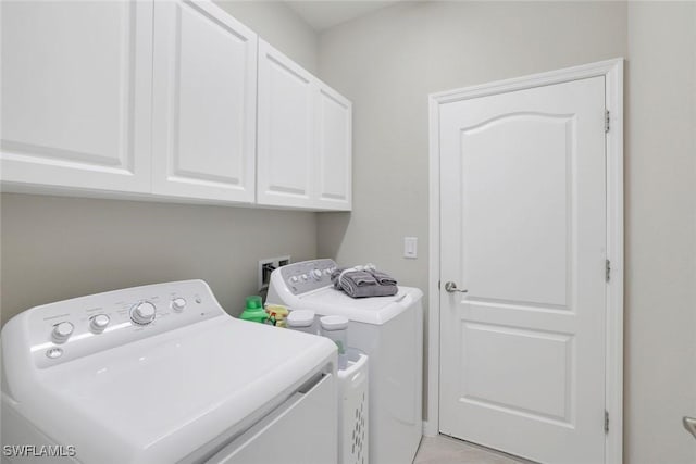 clothes washing area featuring washer and clothes dryer and cabinet space