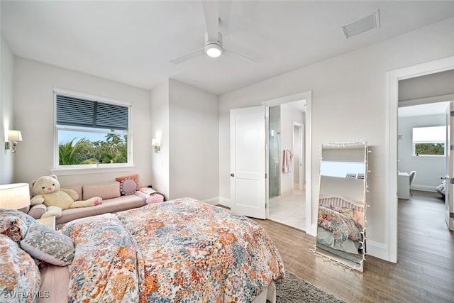 bedroom featuring ensuite bathroom, multiple windows, wood-type flooring, and ceiling fan