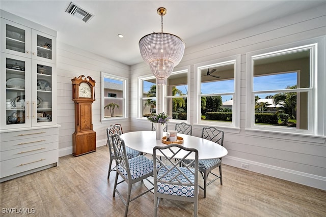 dining space featuring breakfast area, light hardwood / wood-style flooring, and wooden walls