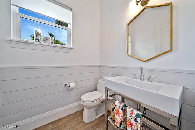 bathroom with toilet, wood walls, and hardwood / wood-style floors