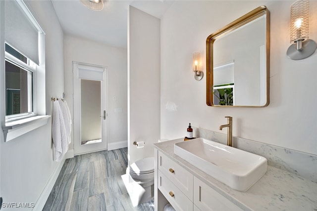 bathroom with wood-type flooring, vanity, and toilet