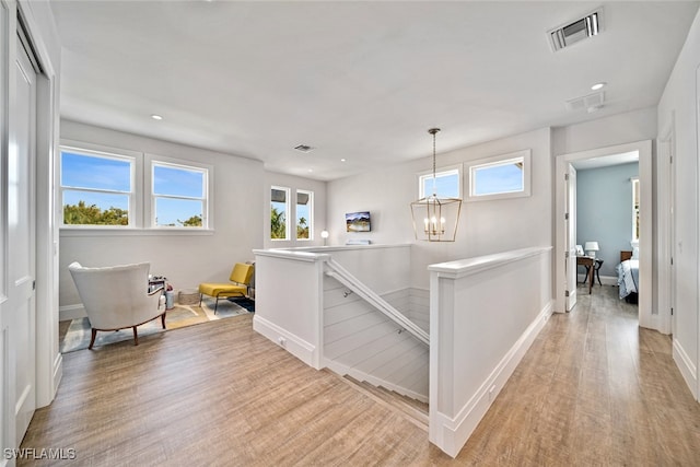 hall with light hardwood / wood-style floors and an inviting chandelier