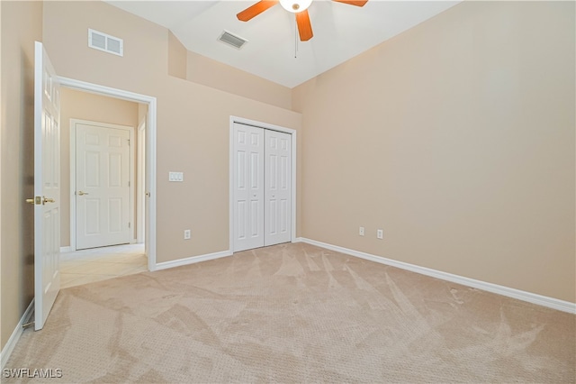 unfurnished bedroom with vaulted ceiling, light colored carpet, ceiling fan, and a closet