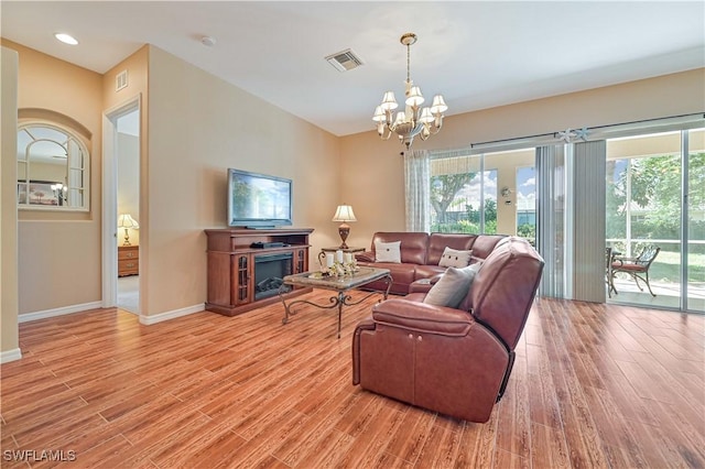 living room with a notable chandelier, a wealth of natural light, and light wood-type flooring