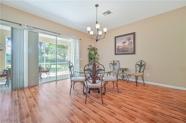 dining area featuring hardwood / wood-style flooring and an inviting chandelier