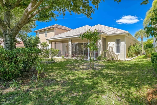 rear view of property featuring a sunroom and a lawn