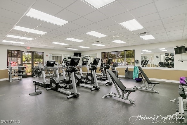 gym featuring a paneled ceiling and a healthy amount of sunlight