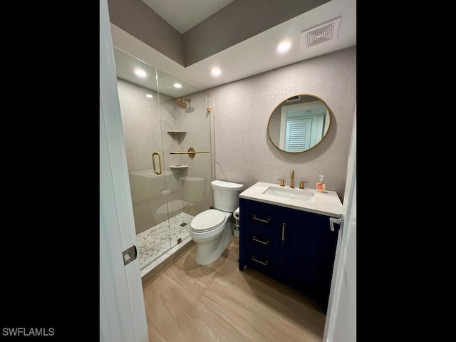 bathroom with a shower with door, vanity, and toilet