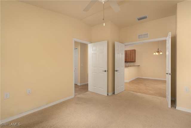 unfurnished room featuring ceiling fan with notable chandelier, lofted ceiling, and light carpet