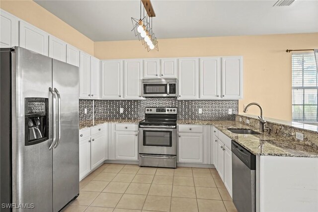 kitchen with white cabinets, sink, appliances with stainless steel finishes, decorative light fixtures, and kitchen peninsula