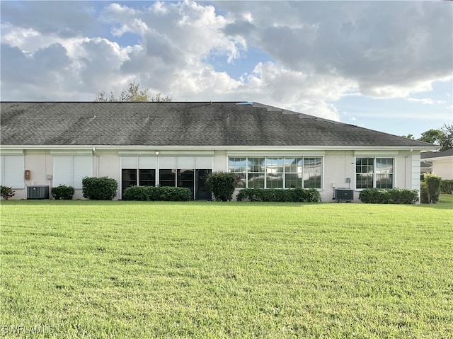 rear view of property with central AC and a yard