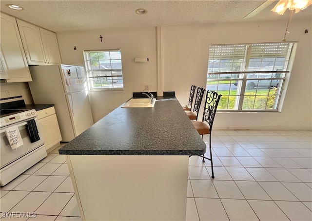 kitchen with white cabinets, white appliances, sink, and light tile patterned flooring