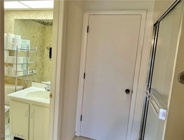 bathroom with a shower with door, vanity, and toilet