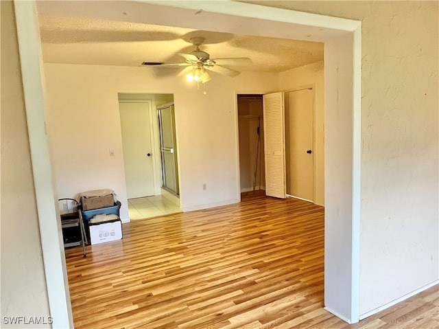 spare room featuring a textured ceiling, light hardwood / wood-style floors, and ceiling fan