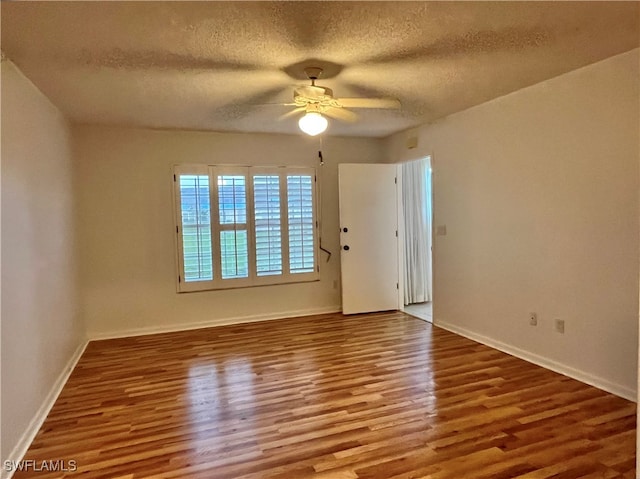 empty room with ceiling fan, wood-type flooring, and a textured ceiling