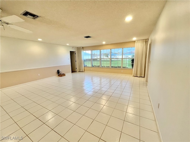 tiled empty room with a textured ceiling and ceiling fan