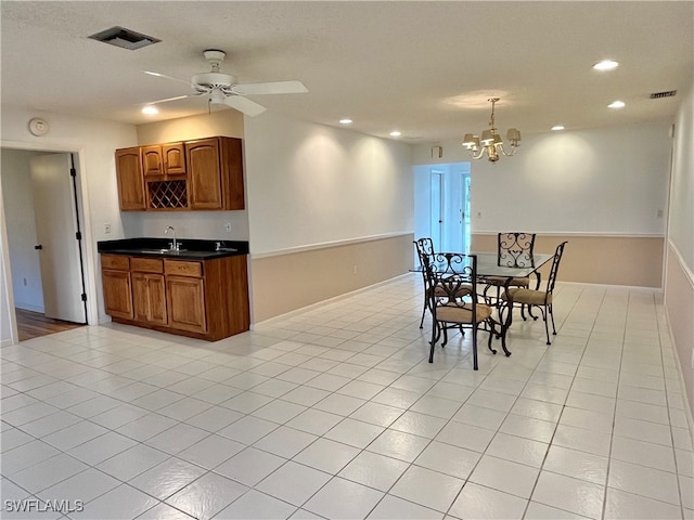 tiled dining area with ceiling fan with notable chandelier and sink