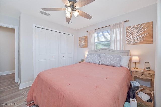 bedroom with light hardwood / wood-style flooring, ceiling fan, and a closet