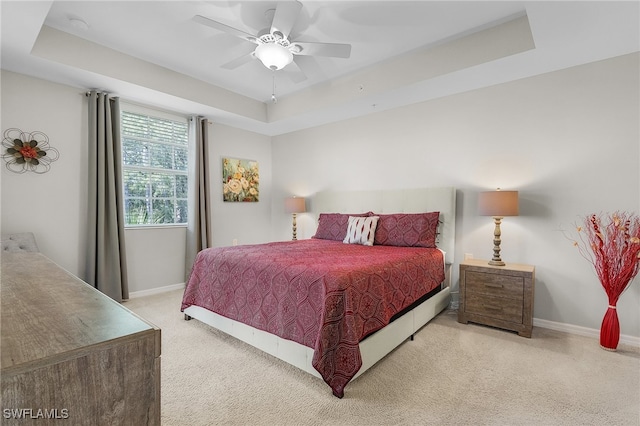 bedroom featuring light carpet, ceiling fan, and a raised ceiling