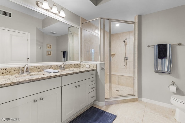 bathroom featuring toilet, vanity, tile patterned floors, and a shower with door