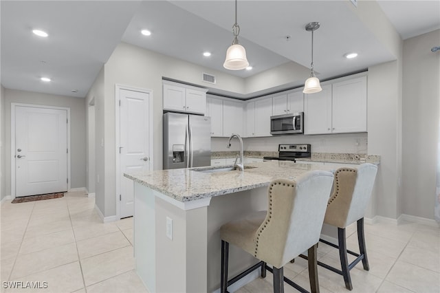 kitchen with white cabinets, stainless steel appliances, a center island with sink, and sink