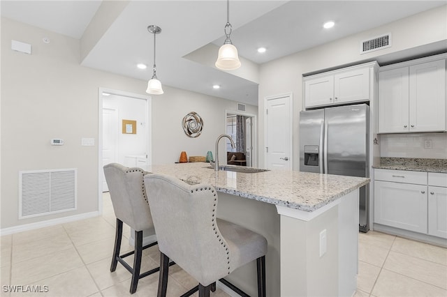 kitchen featuring backsplash, a kitchen island with sink, stainless steel fridge with ice dispenser, and pendant lighting