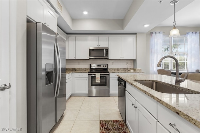 kitchen with appliances with stainless steel finishes, pendant lighting, light stone countertops, sink, and white cabinets