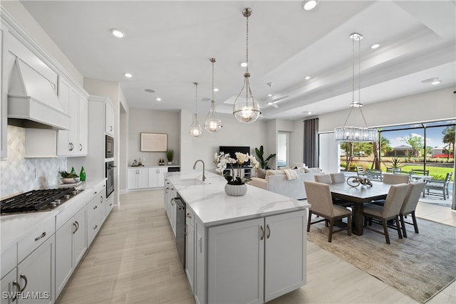 kitchen featuring backsplash, a spacious island, decorative light fixtures, custom range hood, and stainless steel appliances