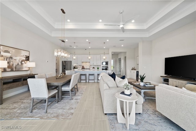 living room featuring ceiling fan, a raised ceiling, ornamental molding, and light tile patterned floors