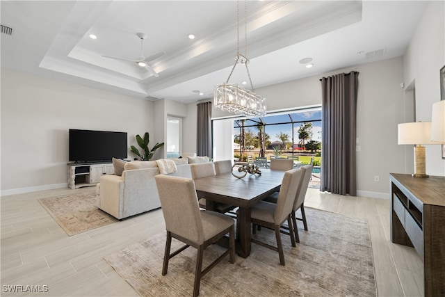 dining space with ceiling fan, light wood-type flooring, crown molding, and a tray ceiling