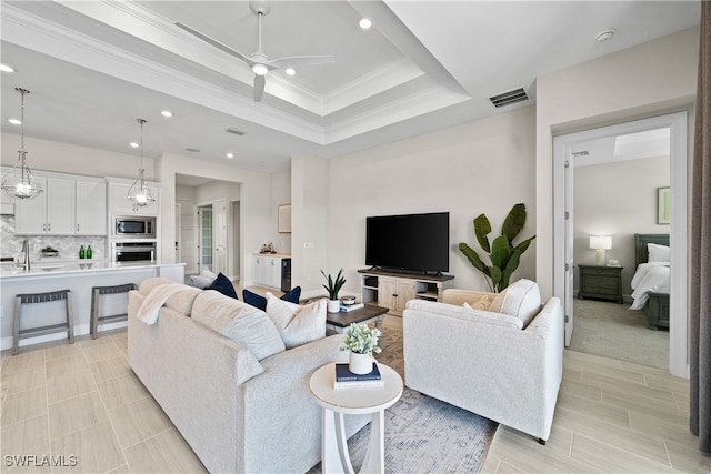 living room with light carpet, ornamental molding, a raised ceiling, ceiling fan, and sink