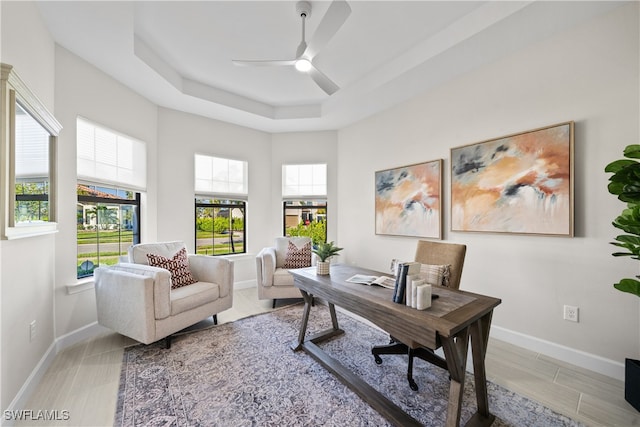 home office featuring a raised ceiling and ceiling fan