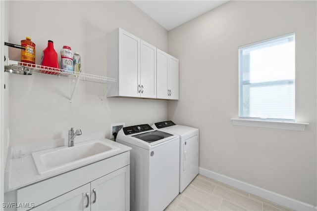 laundry area featuring cabinets, washer and clothes dryer, and sink