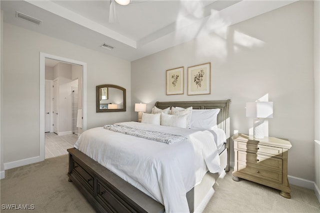 bedroom with ceiling fan, light carpet, and ensuite bath