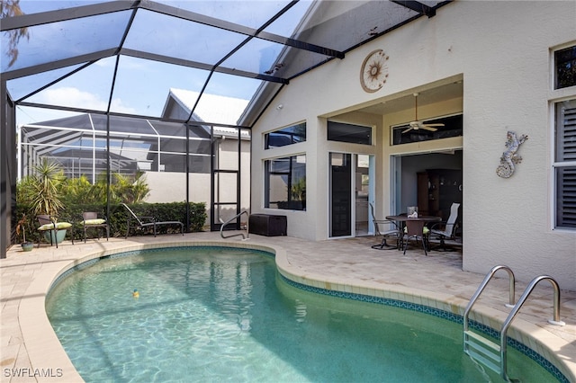 view of pool featuring glass enclosure, a patio, and ceiling fan