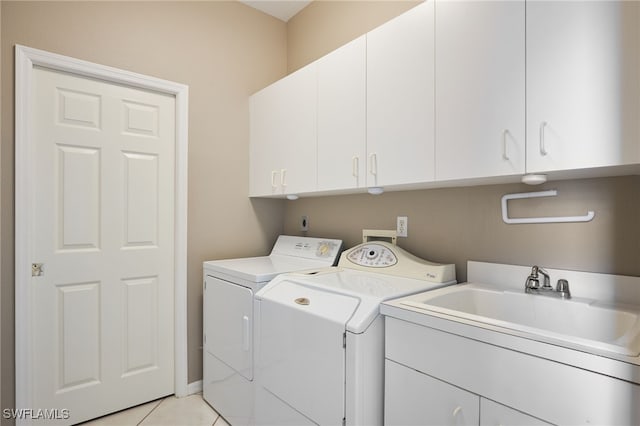 clothes washing area featuring washing machine and dryer, cabinets, sink, and light tile patterned flooring