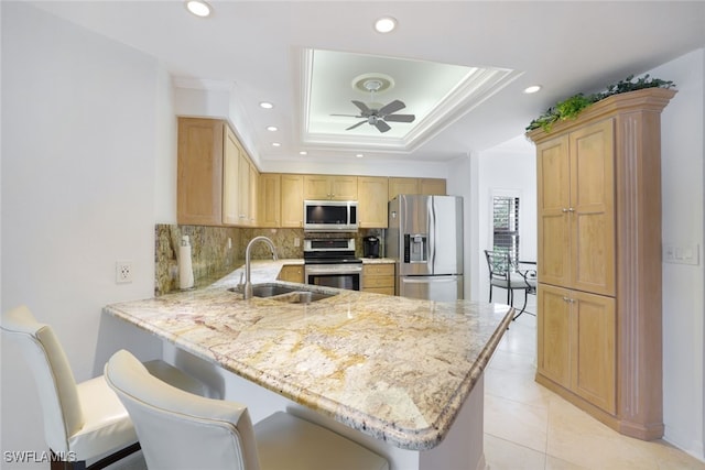 kitchen with kitchen peninsula, stainless steel appliances, ceiling fan, sink, and a breakfast bar area