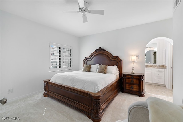 bedroom with connected bathroom, light colored carpet, and ceiling fan