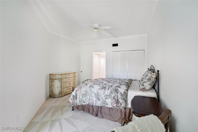 bedroom featuring ceiling fan, a closet, crown molding, and light carpet